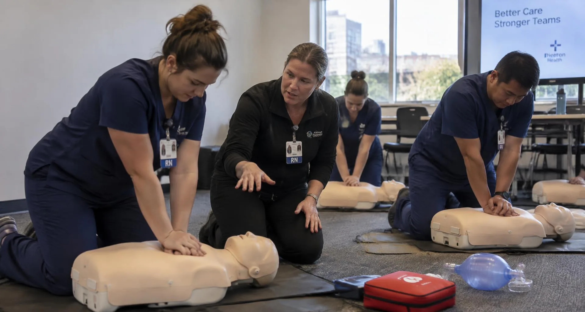 Illustrative scene of nurses practicing CPR compressions with an instructor in a hospital conference room